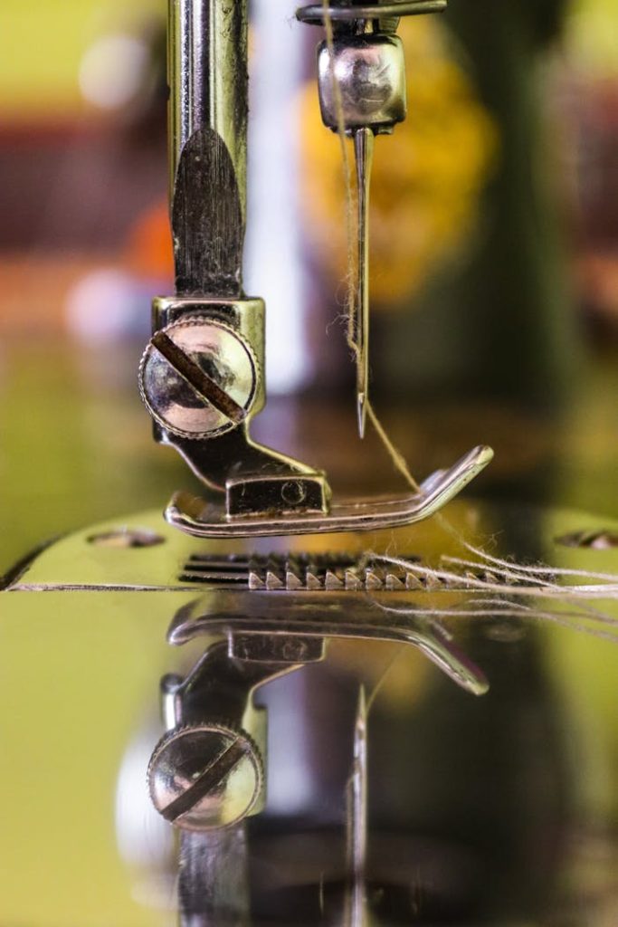 Detailed view of a sewing machine needle threading cloth, showcasing industrial precision.